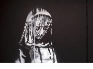 Banksy graffiti of a shrouded, mourning woman painted in white on a black door