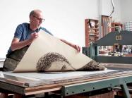 man pulls print off press