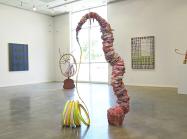 Installation view of Evenso: The Common & The Curious, showing sculpture in center of room and works on walls