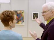 Steve Martin looks closely at work of art on wall