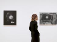 Curator walks through gallery of black and white images.