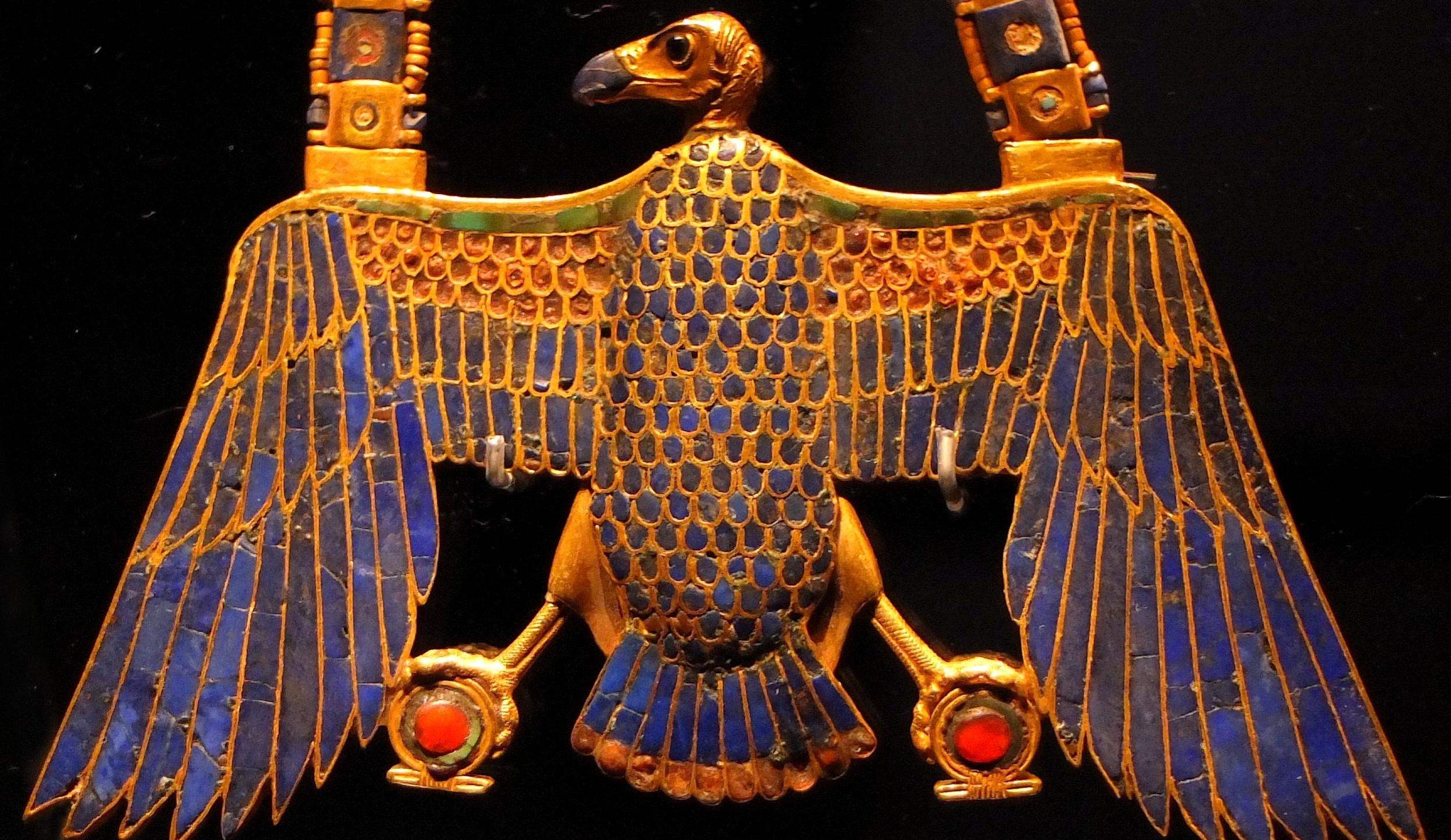  A golden amulet in the form of a vulture with outstretched wings, representing the ancient Egyptian goddess Nekhbet, who was associated with wealth and prosperity.