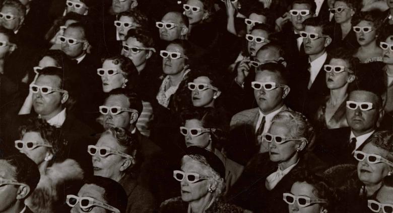 Audience watches movie wearing 3-D spectacles, 1952