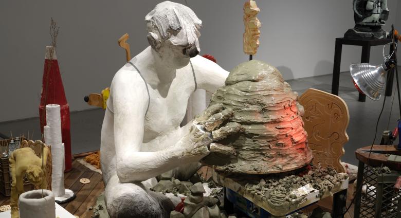 Nicole Eisenman, Maker's Muck, 2022. Coney Island Boardwalk (Brazilian Ipe), plaster, bronze, silicone, unfired clay, fired clay, expanding foam, burlap, wire, raw wool, sneakers, magic smooth, magic sculpt, resin, bamboo skewers, tin foil, plaster bandages, plywood, bass wood, Aqua-Resin, fiberglass, seashell, styrofoam, oil paint, wax, carpet fringe, cardboard, cement, steel pipe, steel rod, aluminum paint tubes, vinyl stickers, granite, telescopic extension pole, sand, fabric, crocheted rug, marbles, min