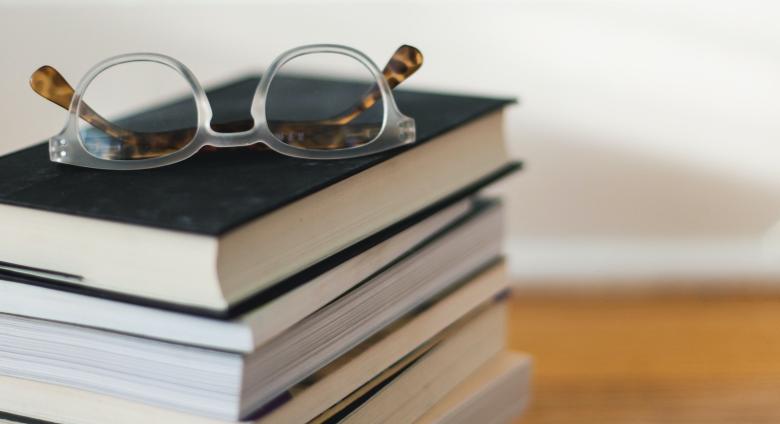 stack of books with pair of reading glasses on top
