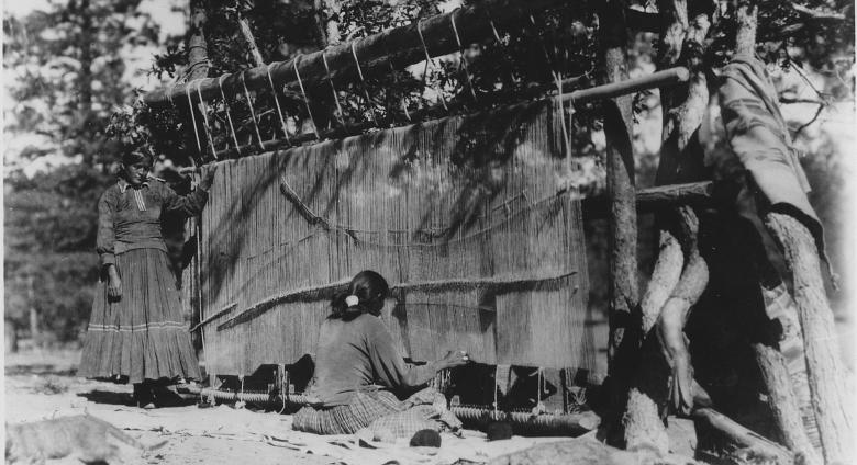 Navajo women weaving a rug c.1930-1938. Source.