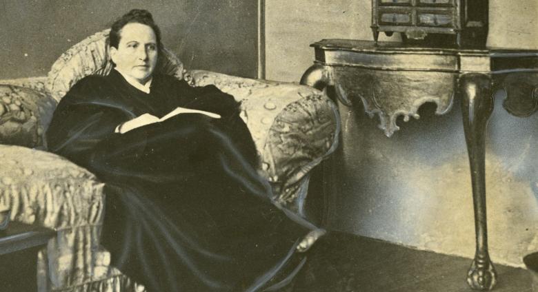 Wide World Photos, detail of Gertrude Stein sitting on a sofa in her Paris studio, with a portrait of her by Pablo Picasso, and other modern art paintings hanging on the wall behind her, May 1930. 