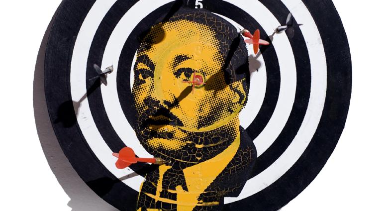a dart board with martin luther king's portrait screenprinted on top in orange and black. 