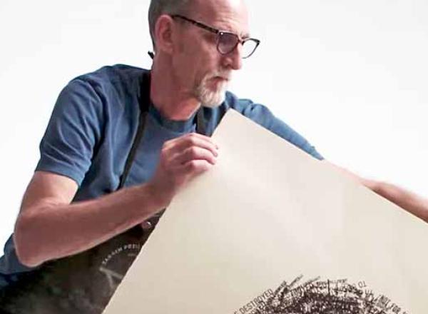 man pulls print off press