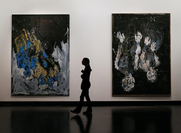 a silhouetted figure walks between two large abstract paintings