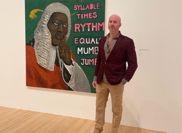 Jeffrey Magid standing in front of Henry Taylor's / was King When I Met the Queen, Syllable x Rythm Equals Mumbo Jumbo, 2013.