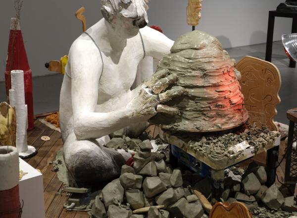 Nicole Eisenman, Maker's Muck, 2022. Coney Island Boardwalk (Brazilian Ipe), plaster, bronze, silicone, unfired clay, fired clay, expanding foam, burlap, wire, raw wool, sneakers, magic smooth, magic sculpt, resin, bamboo skewers, tin foil, plaster bandages, plywood, bass wood, Aqua-Resin, fiberglass, seashell, styrofoam, oil paint, wax, carpet fringe, cardboard, cement, steel pipe, steel rod, aluminum paint tubes, vinyl stickers, granite, telescopic extension pole, sand, fabric, crocheted rug, marbles, min