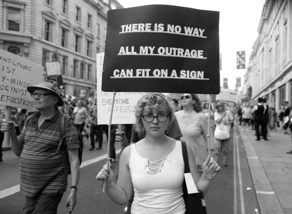 Woman marching holds a sign that says there is no way all my outrage can fit on a sign.