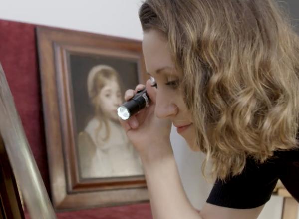 expert examines painting with flashlight