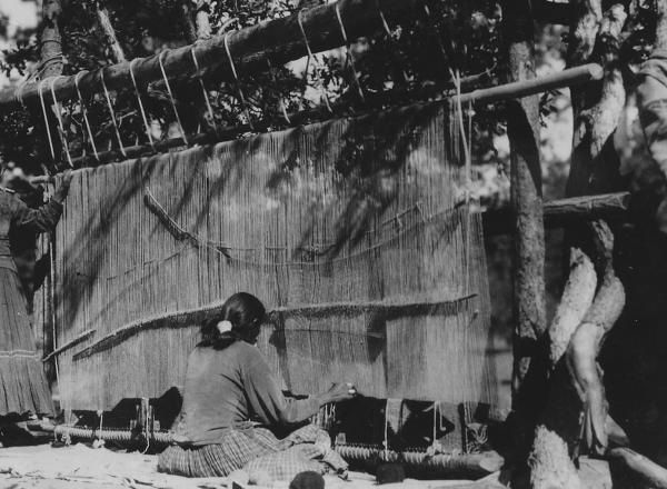 Navajo women weaving a rug c.1930-1938. Source.