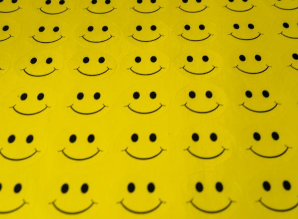 a sheet of yellow fabric with rows and rows of smiley faces