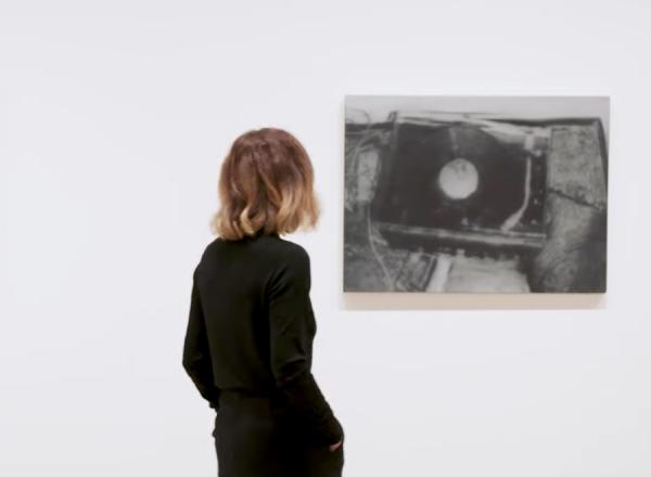 Curator walks through gallery of black and white images.