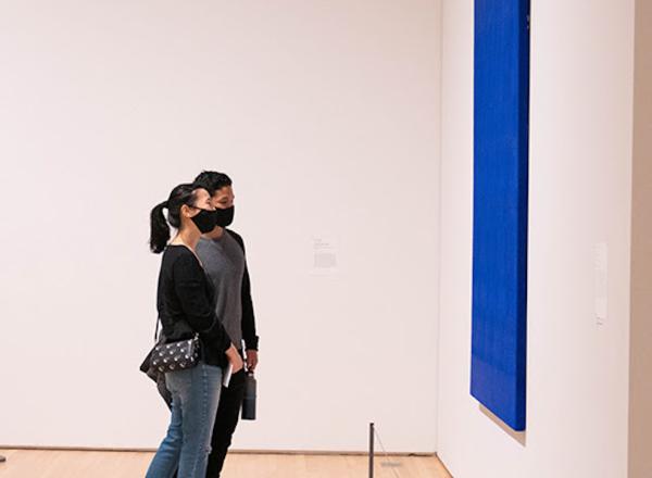 Visitors inside of SFMOMA, looking at paintings 