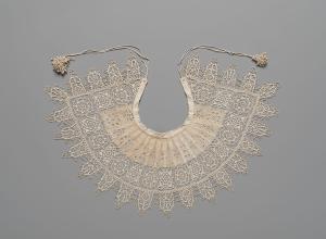 Detailed and petite lace collar. Unknown, 1610-1620, Standing Band (Collar) with Tassels, Cutwork, needle lace, reticello, punto in aria, embroidery, linen. Gift of Mrs. Edward S. Harkness, 1930. The Metropolitan Museum of Art. .