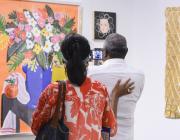 A couple at the Affordable Art Fair NYC, taking a photo of a bright, contemporary still life floral painting. 