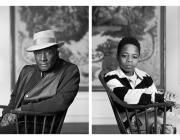 Black and white photo of seated Fred Stewart II and Tyler Collins. Both look at camera.