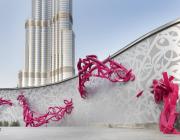 View of sculptural installation "declaration" featuring red and silver text along a scrolling wall. 