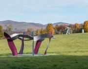 view of multiple sculptures in the park in front of a mountainous fall landscape. 
