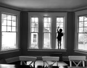 the silhouette of a child standing in a bay window
