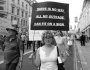 Woman marching holds a sign that says there is no way all my outrage can fit on a sign.