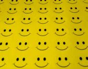 a sheet of yellow fabric with rows and rows of smiley faces