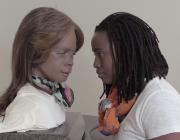 photo of a woman and a silicone clone of herself looking each other in the eye