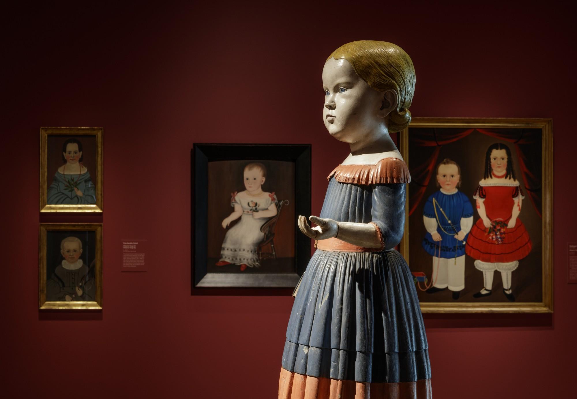 art gallery with sculpture of a child and portraits of children