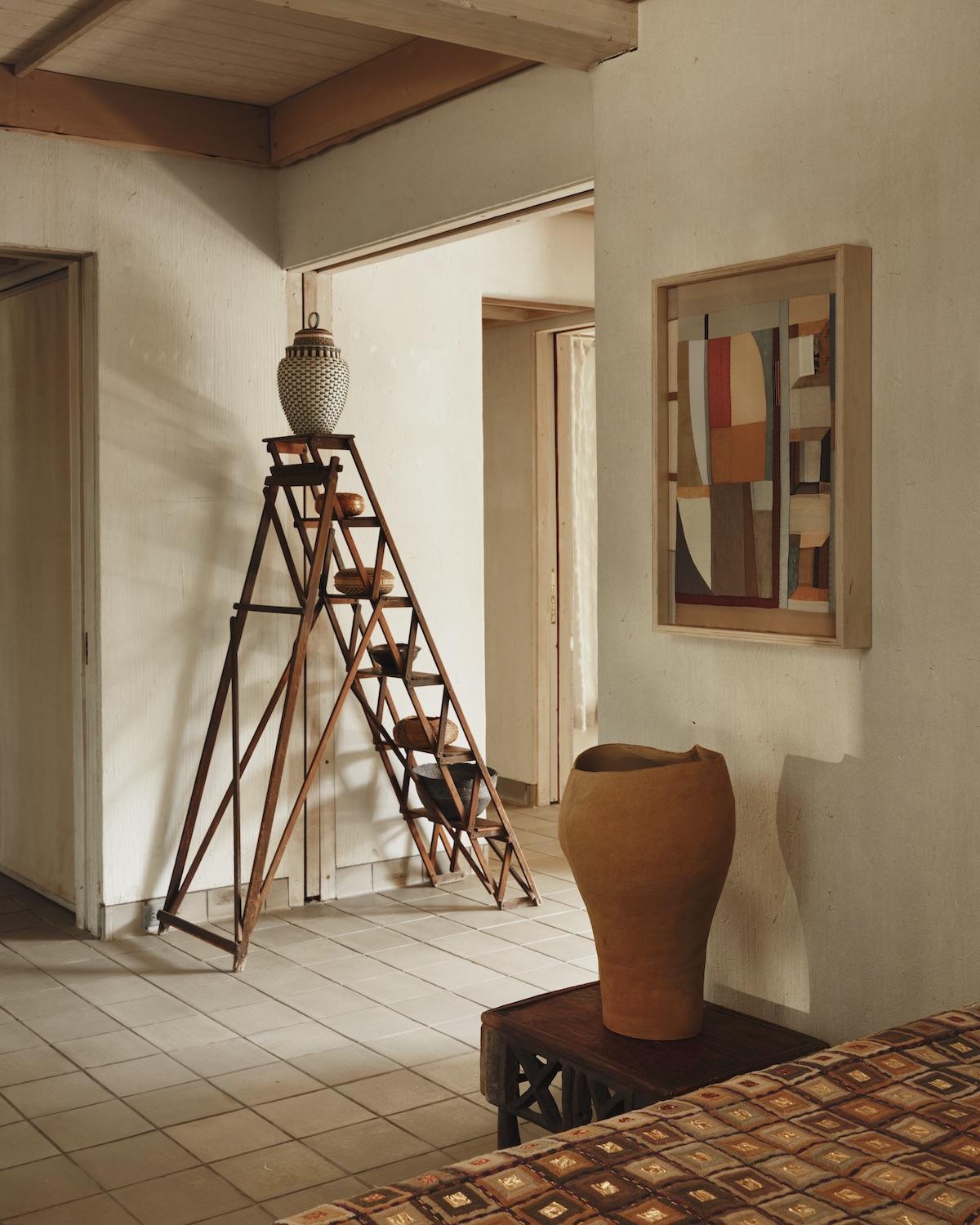 A Summer Arrangement: Object & Thing at LongHouse. LongHouse, East Hampton, New York. Photo by Adrian Gaut. Works pictured: [back wall]: ladder and baskets from the collection of LongHouse with a work by Jeremy Frey on the top rung; [wall] Kiva Motnyk, Light Reflections (2023); [side table] Ludmilla Balkis, Monochrome No. 04, (2021); [bed] Jack Lenor Larsen, Magnum (1970).