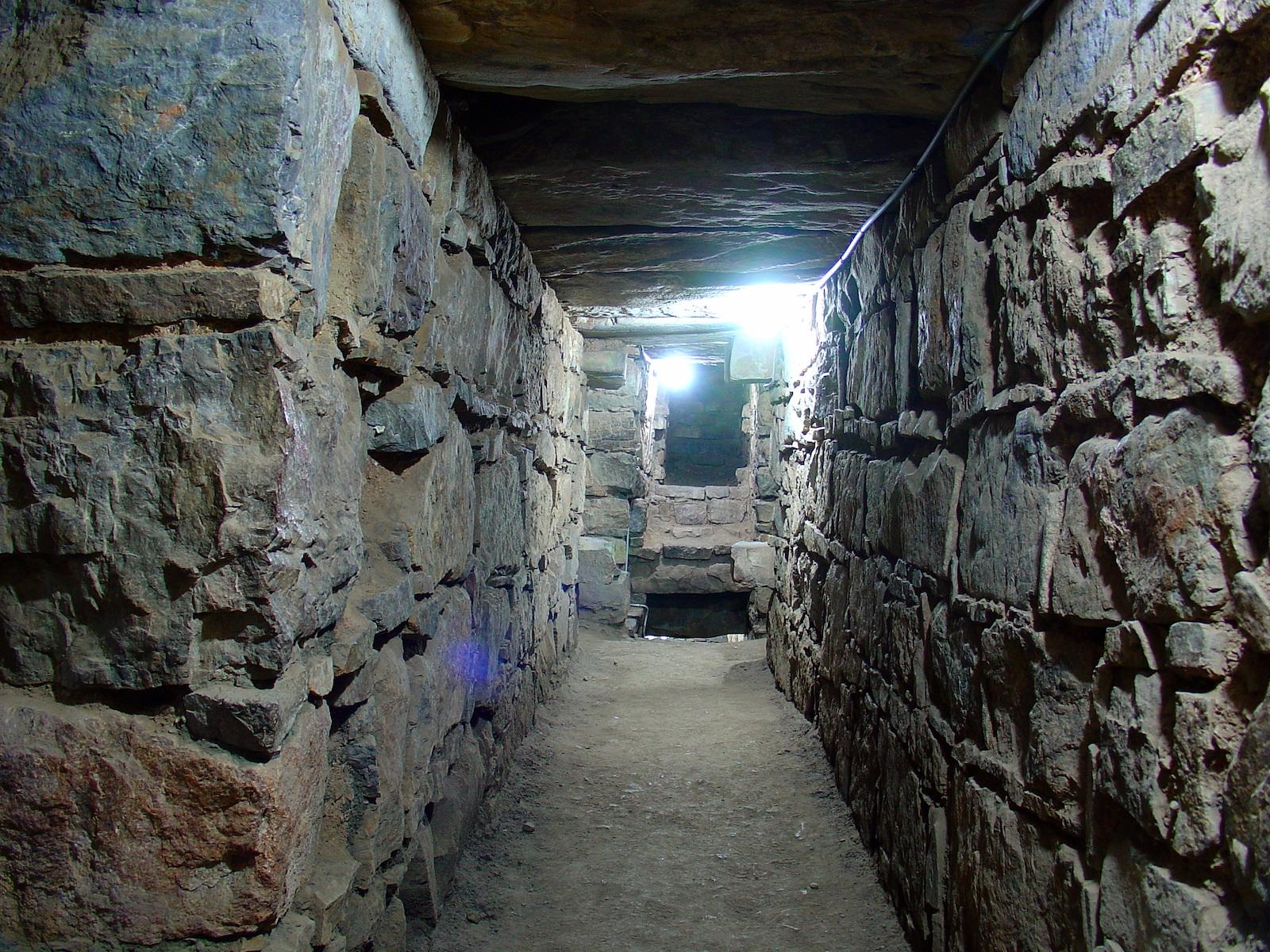 Photo of an interior passage of Chavín de Huántar. The walls appear to be made from stacks of large stone cubes, most layers are separated by thin, flat stones.