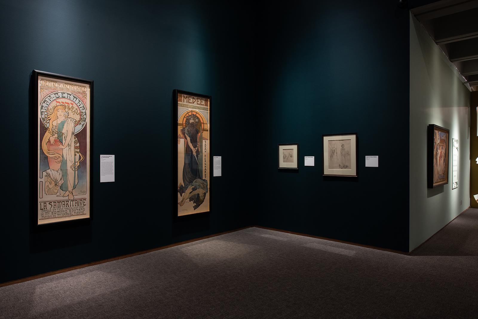 Installation view of Alphonse Mucha: Art Nouveau Visionary featuring Medea (1898) and The Samaritan (1897).