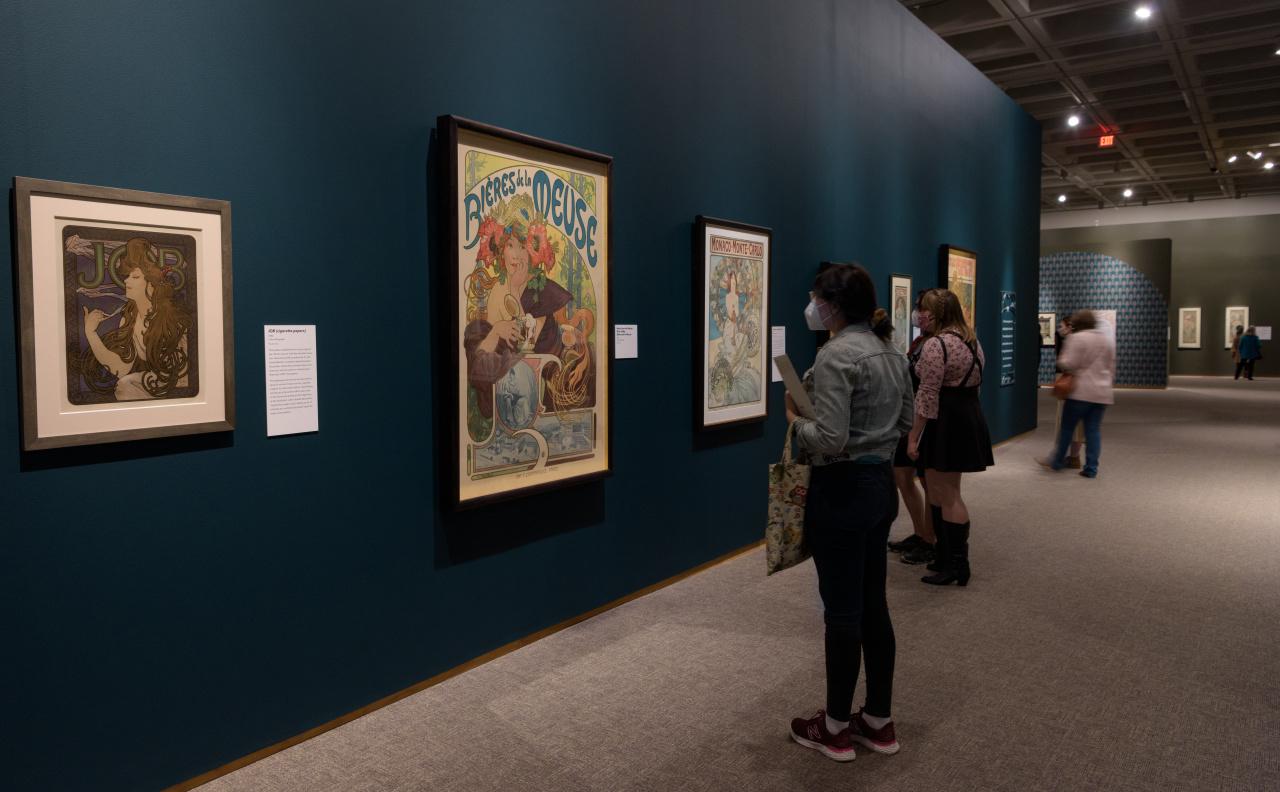 Installation view of Alphonse Mucha: Art Nouveau Visionary featuring a Mucha JOB cigarette papers advertisement (1896).