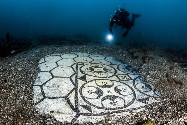  A diver reveals a pristinely preserved mosaic floor at the underwater site of Baiae in Italy. Credit: SuBaia.com