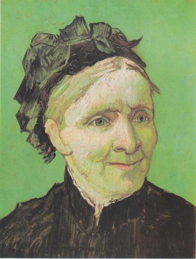 The artist mother looks to the side with a smile. She is dressed in black and shown in front of a green background. 
