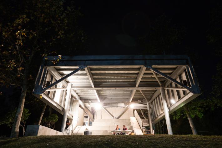 young people sit under a large structure at night