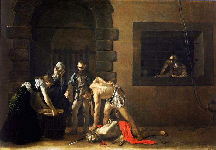 A man stands dispassionately above a prone, bleeding, lifeless body while others look on. 