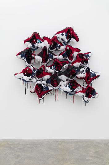 wall-mounted art piece comprised of jordans that appear to be falling apart and/ or gruesomely splattered.