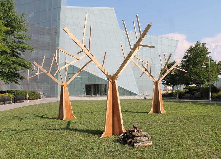 photograph of MICA's Cohen Center, a modern, angular glass building with three tree-like steel sculptures in front of it
