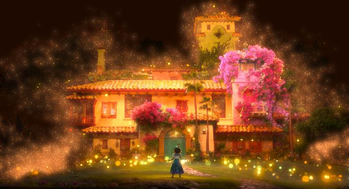 A promotional image of Mirabel standing in front of the magical home of the Madrigals.