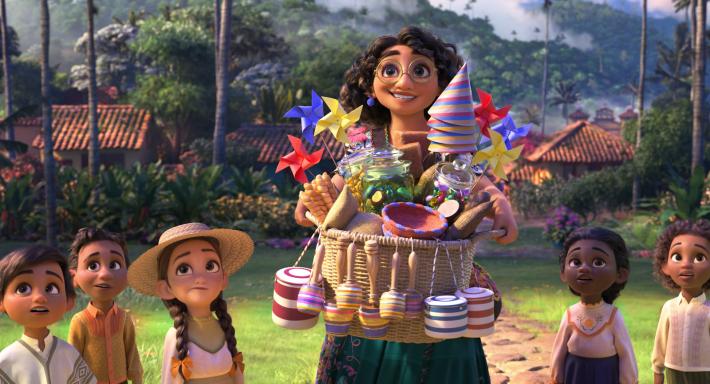 Film still of Mirabel carrying a basket filled with party items in the colors of the Colombian flag. 