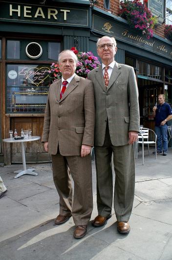 couple dressed in nearly matching suits pose on street corner 