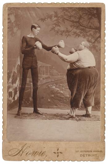 antique photograph of a tall skinny man and short large man boxing