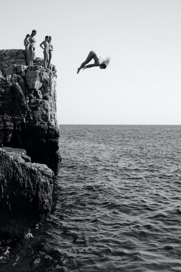 "A young girl shows off her skills, diving from a cliff on the island of Lokrum in Croatia."