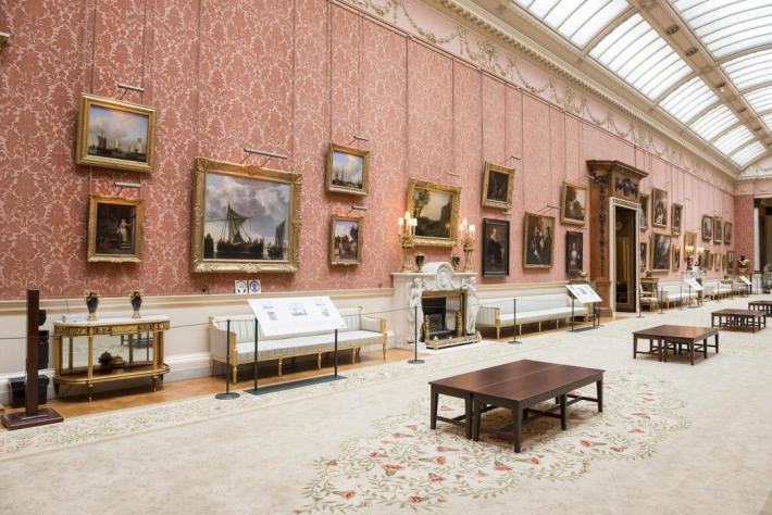 The picture gallery of buckingham palace- a large room with pink walls and many paintings