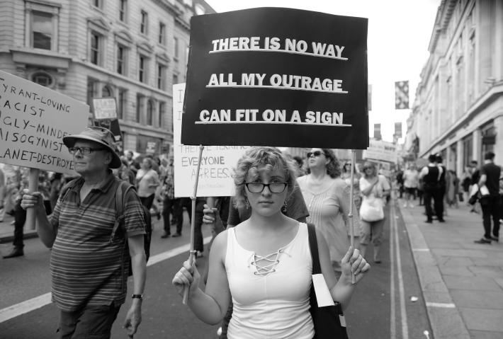 Woman marching holds a sign that says there is no way all my outrage can fit on a sign.