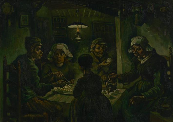 A family sits around a table to eat in a darkly-light, nearly green room 